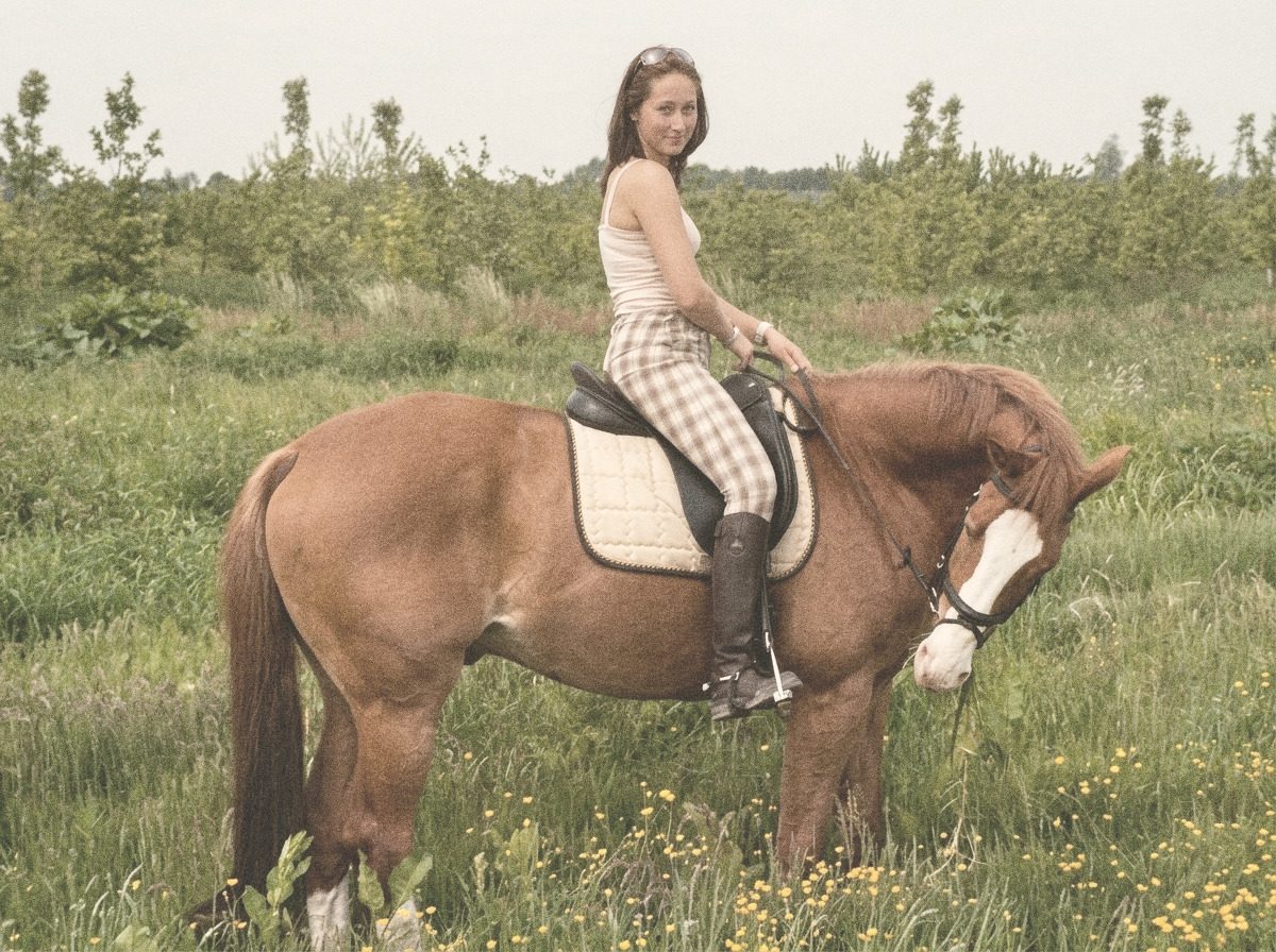 Nicky te paard op Kafka tijdens een buitenrit door een weiland