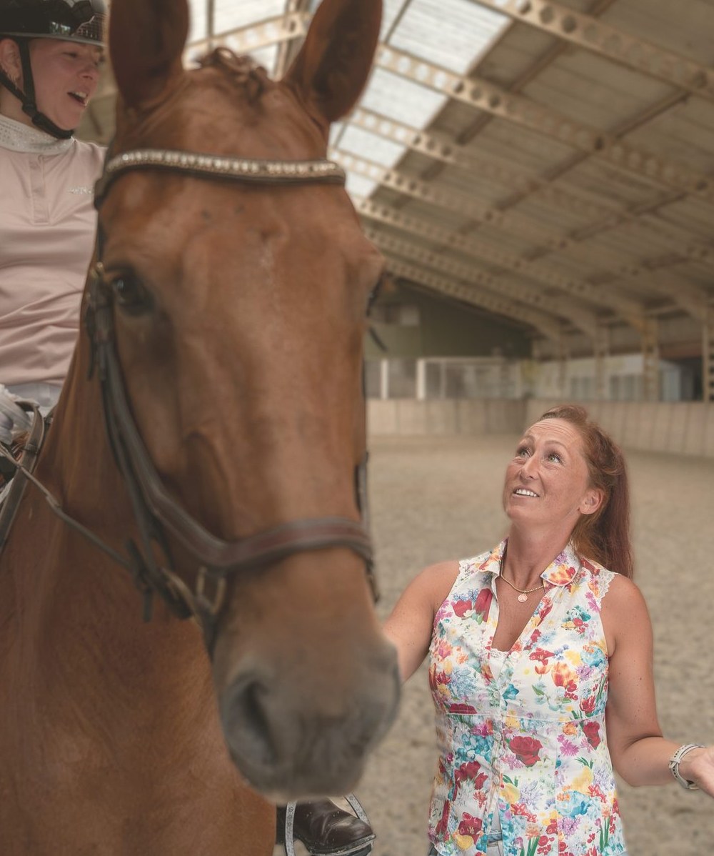 Nicky geeft les aan een ruiter te paard in de binnenbaan